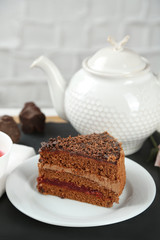 Sliced chocolate cake on plate, on wooden table  background
