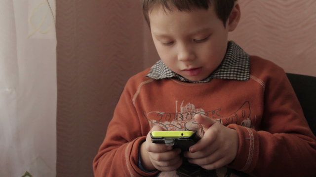 ittle boy playing a game on your smartphone