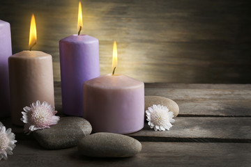 Fototapeta na wymiar Spa set with candles, pebbles and flowers on wooden background, close up