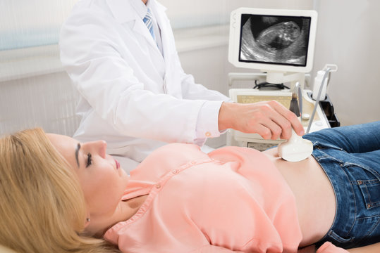 Doctor Moving Ultrasound Transducer On Pregnant Woman's Stomach