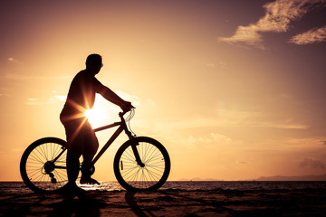 Naklejka na ściany i meble happy man standing on the beach at the sunset