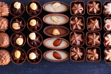 Delicious chocolate candies on blue wooden background, close up
