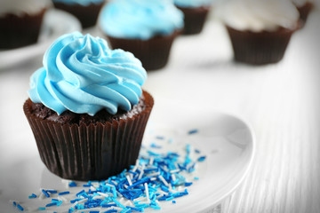 Delicious chocolate cupcake with blue cream on decorated wooden  table, close up