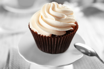 Delicious chocolate cupcake with cream on served table, close up