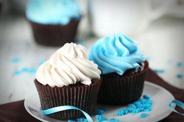 Chocolate cupcakes with colourful cream on decorated table , close up