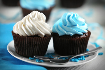 Chocolate cupcakes with colourful cream on served table, close up