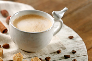 Cup of coffee with sugar and cinnamon on white wooden mat