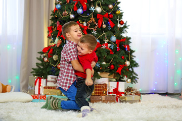 Obraz na płótnie Canvas Two cute small brothers hugging on Christmas tree background
