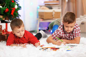 Two cute small brothers drawing on Christmas tree background