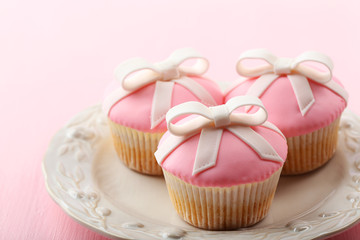 Tasty cupcakes with bow on color wooden background
