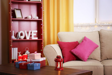 Colourful decorated interior. Comfortable living room, table with gift boxes and candles on it is close up