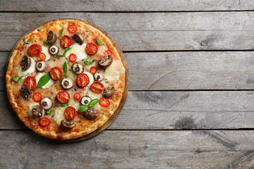 Obraz na płótnie Canvas Tasty fresh pizza decorated with mushrooms and tomatoes on wooden background, close up