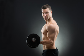 Confident Muscular Man Lifting Dumbbell