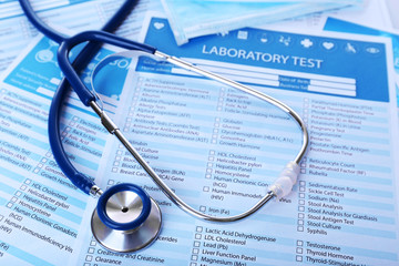 Stethoscope and medical mask on laboratory test lists, close up