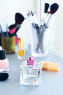 Perfume bottle with makeup tools and cosmetics on a table