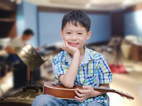 Asian boy with ukulele at music school
