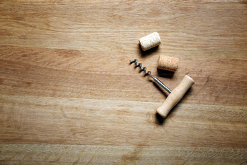 Two wine corks and corkscrew on wooden background