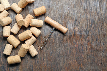 Wine corks and corkscrew on old wooden background, close up