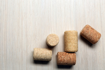 Five wine corks on light wooden background, close up