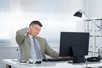 Businessman Suffering From Neck Pain At Desk