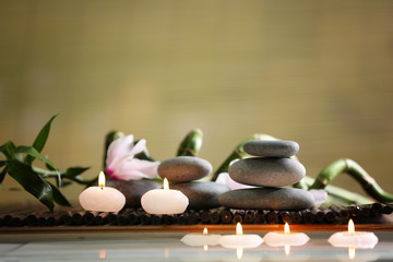 Fototapeta na wymiar Spa still life with stones, candles and flowers in water on blurred background