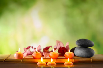 Spa still life with stones, candles and flowers in water on natural blurred background