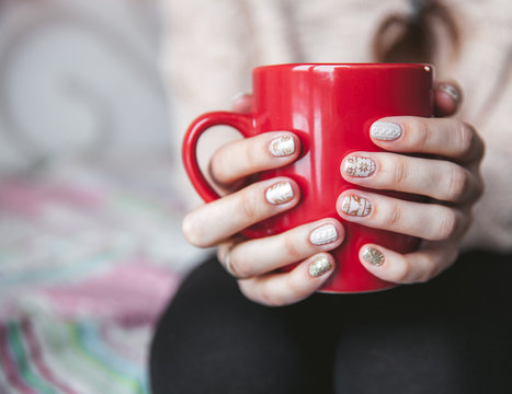 Woman's Hand Holding A Red Cup Of Coffee. With A Beautiful Winter Manicure. Drink, Fashion, Morning