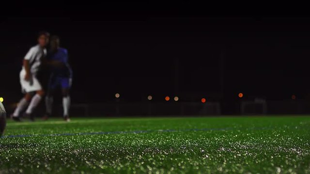 Close up of a soccer ball being kicked in slow motion at night