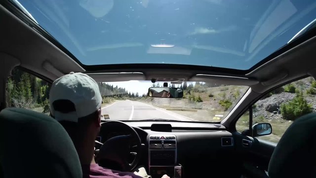 man driving a car on country road trip in nature with sunset and sun flare, navigating with  smart phone navigation application