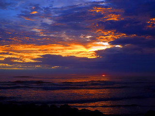 Cloudy Sunset Over the Ocean with Waves in the Foreground