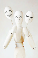 Obraz premium Man holds two masks with different mood. Abstract image with a wooden puppet