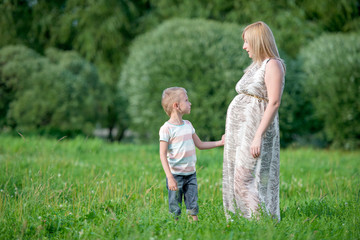Beautiful pregnant woman on a walk with her young son