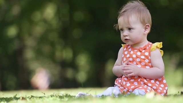 happy newborn baby playing with grass in park at beautiful sunny day