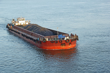 Iron ore mined in hinterland transported to the main harbor in large cargo boat for loading into big ships for exporting in India © JoseMathew