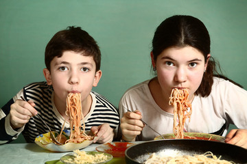 happy teen siblings boy and girl eat spaghetti