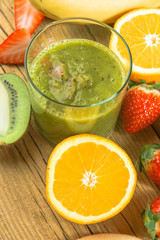 Natural smoothie surrounded by kiwi fruit on wooden base