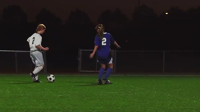 A female soccer player scores a goal during a game at night