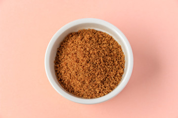 Coconut sugar in a cup with pink background