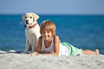 Happy kid with a dog on the beach 