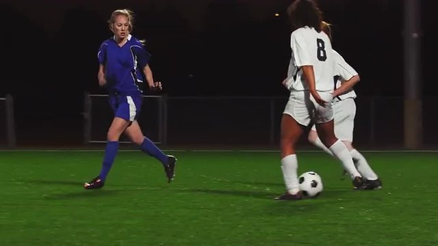 Female soccer players playing a game at night