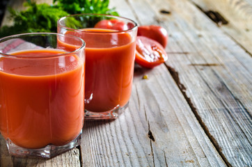 Glass of tomato juice with vegetables on wooden background