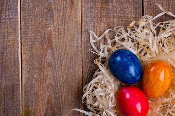 Easter eggs in hay on wooden background.