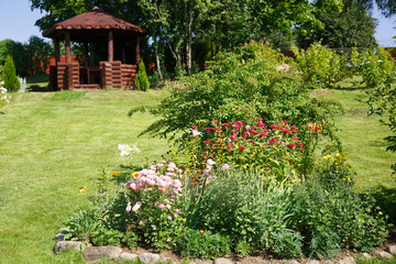 Garden in the summer clear day with flower beds and a gazebo