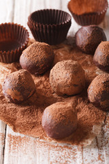 Chocolate truffles in cocoa macro on a wooden table. Vertical
