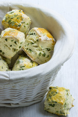 Pikante Scones mit frischen Kräutern in Brotkorb auf weißem Untergrund