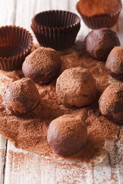 Chocolate truffles in cocoa macro on a wooden table. Vertical

