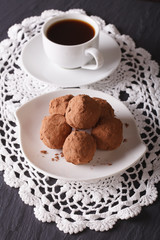 Chocolate truffles on a plate and coffee on the table. vertical
