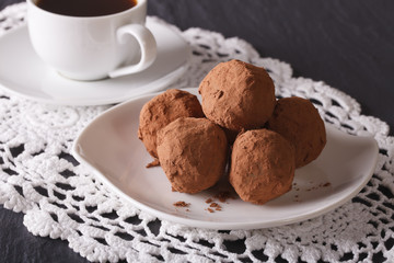 Chocolate truffles on a plate and coffee close-up on the table. 
