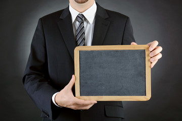 Geschäftmann, Manager oder Chef in Anzug und Krawatte zeigt Tafel mit Textfreiraum und Copy Space