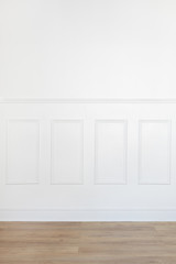 Empty white room with parquet floor and wood trimmed wall